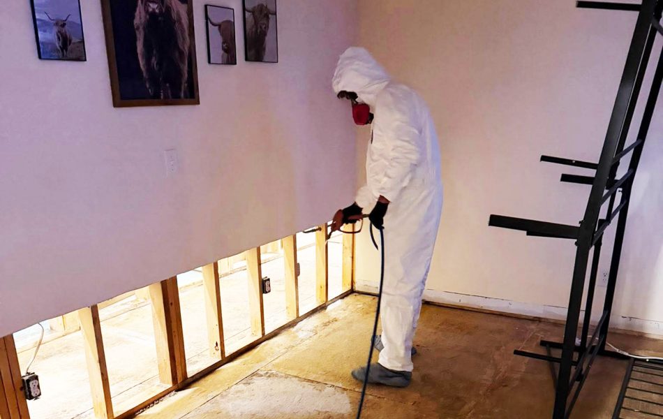 Xtreme Restoration Employee in Hazmat gear removing mold from interior walls